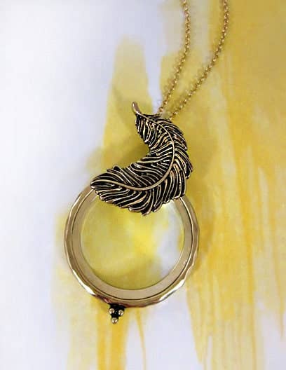 Necklace with a feather pendant on a yellow and white background