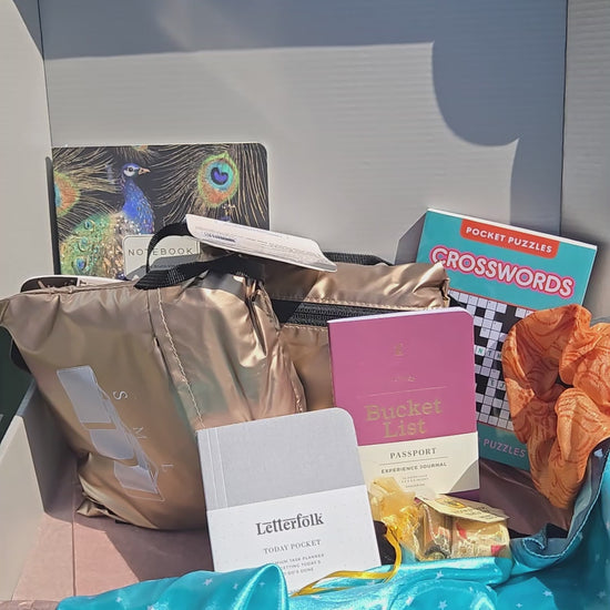 unboxing video of the getaway kit with packed folding duffle, packing cubes, clear tsa friendly waist pack, peacock notebook, hand fan, crossword puzzle, scrunchie and scarf.